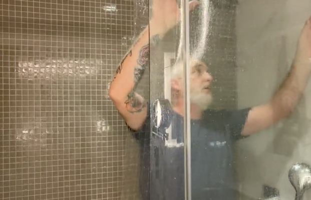 A fitter from The Window Film Company fitting safety window film to a shower door.