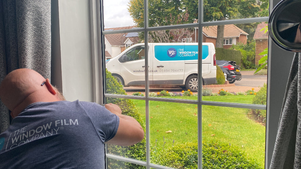 An installer applying window film with a branded van in the background