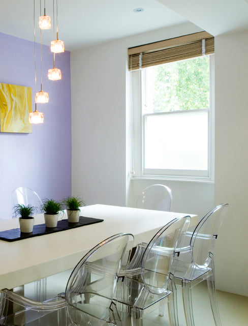 Modern dining room with clear chairs, a white table, and a window with a silver etch frosted window film applied to the lower pane for privacy. 