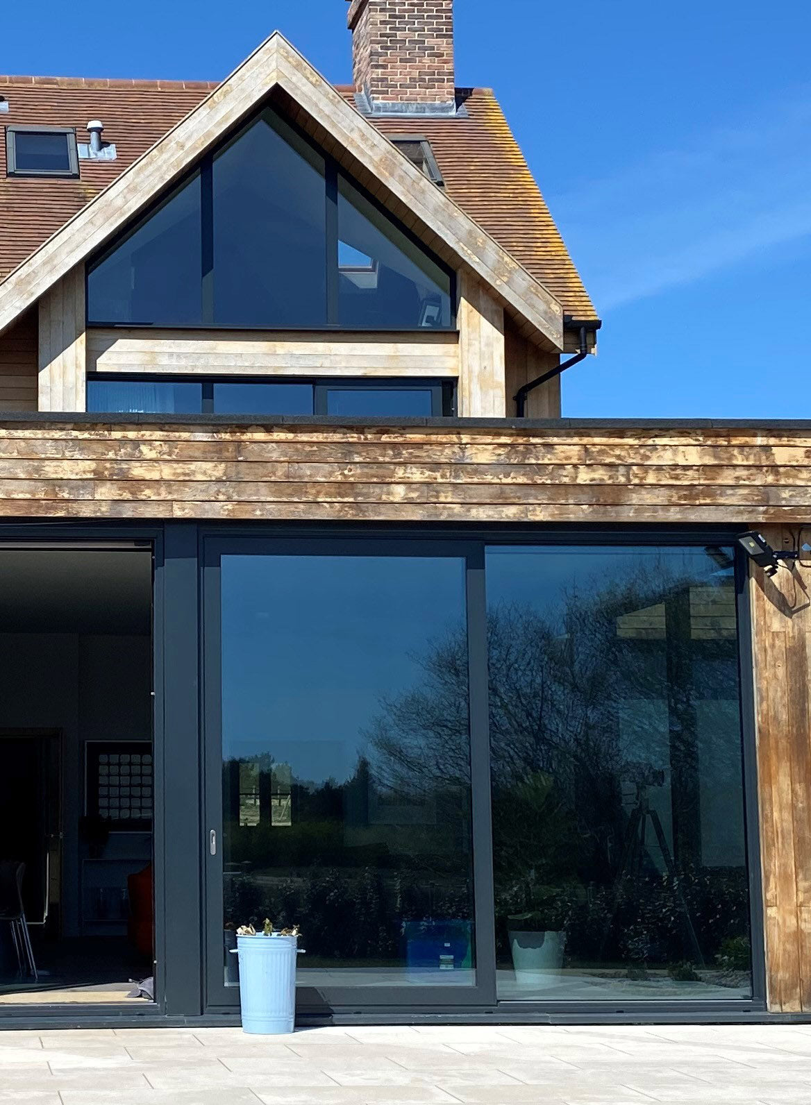 External view of a large modern house with extensive windows on two floors; heat reduction window film has been applied to the glazing on both levels.