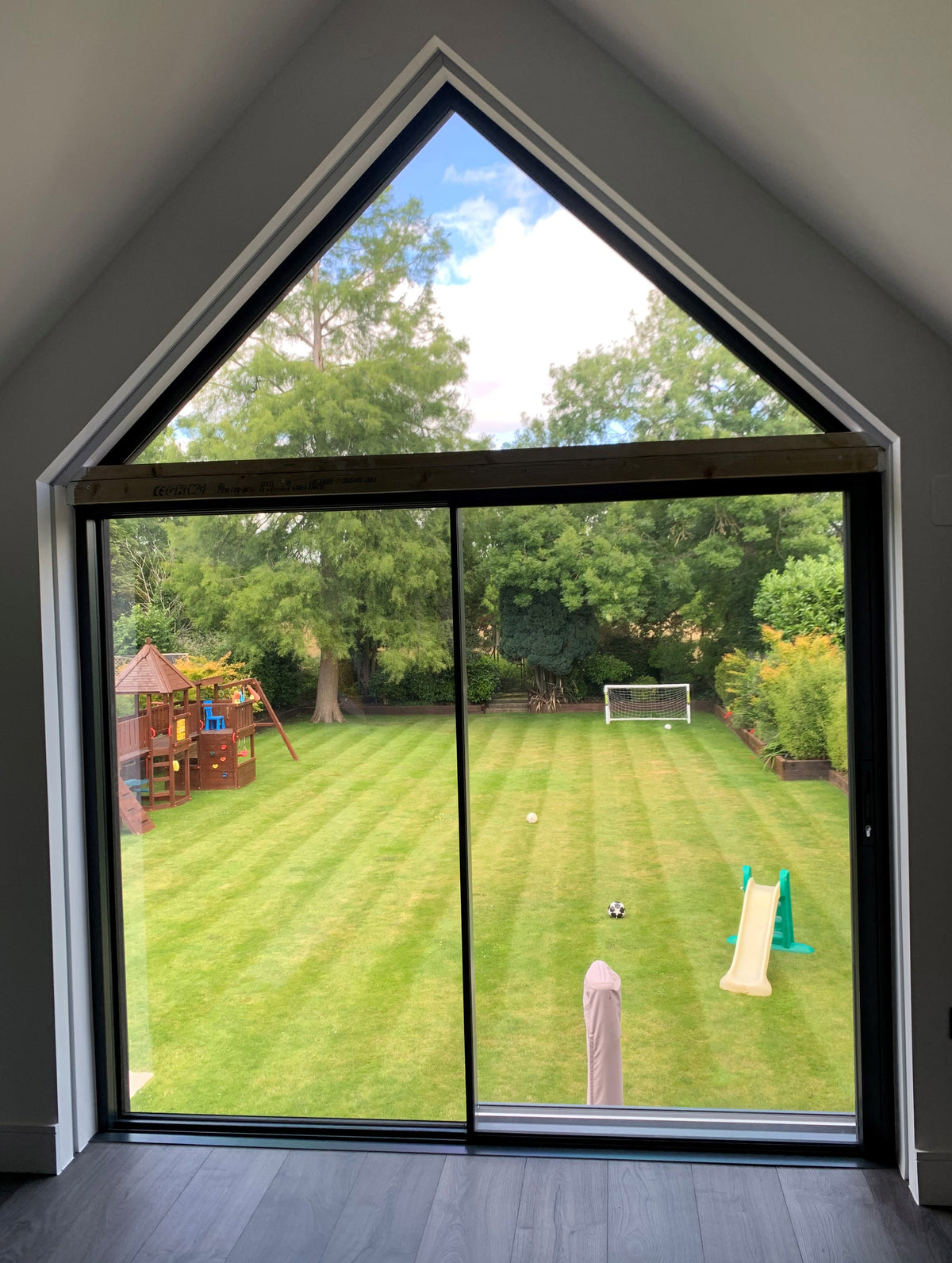 Large window in a residential property looking out over a spacious garden. Heat reduction window film has been applied to the inside of the window.