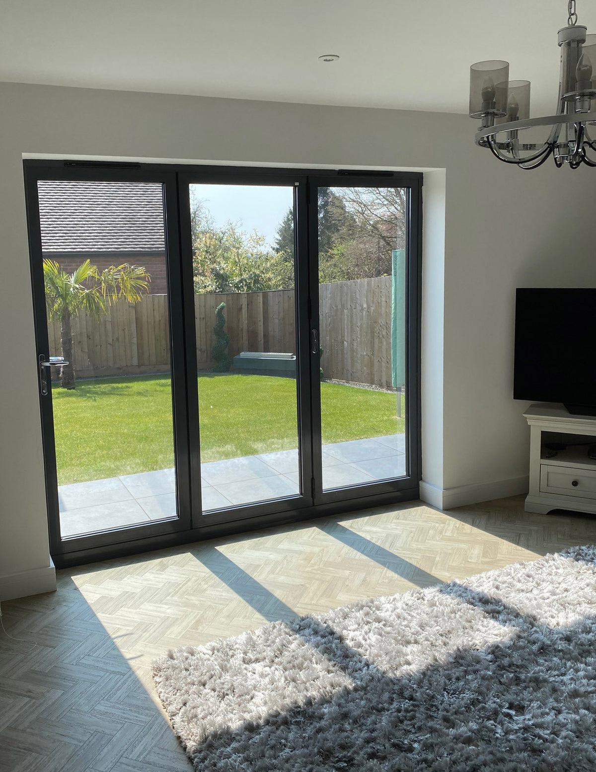 Living room with sliding glass door with heat reduction window film applied to it, leading to a garden