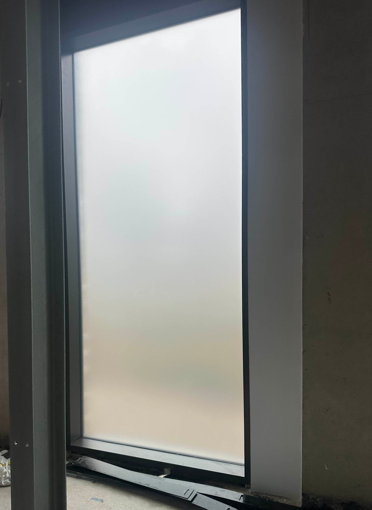 An internal view of a window inside a building undergoing refurbishment. The window has frosted window film applied to give it the appearance of frosted glass.