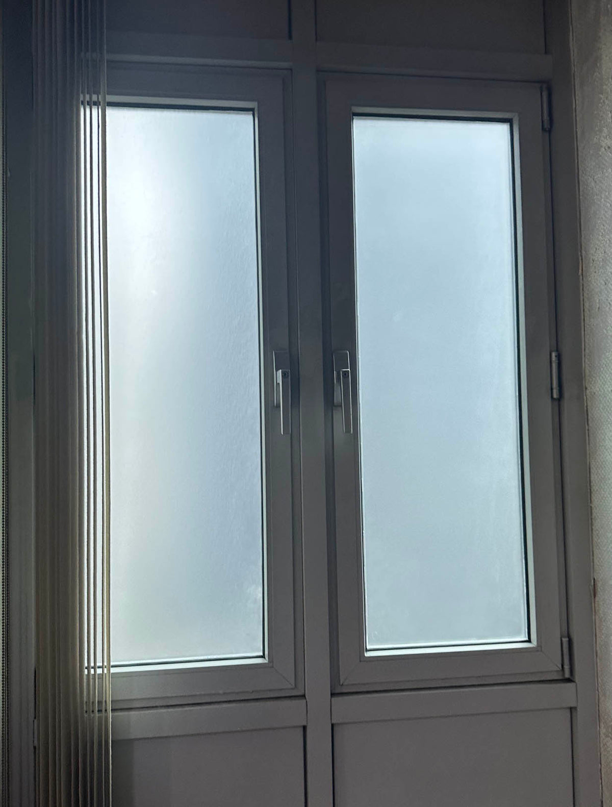 A view of two doors with large glass panels. The panels have frosted window film applied, giving the appearance of frosted glass which blocks the view.