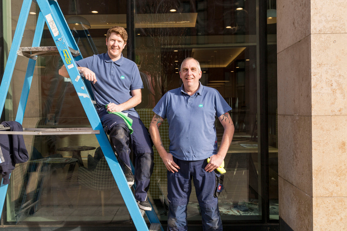 Two fitters from The Window Film Company, wearing Window Film Company uniform, stood outside a completed installation at the Holiday Inn hotel in Manchester. 