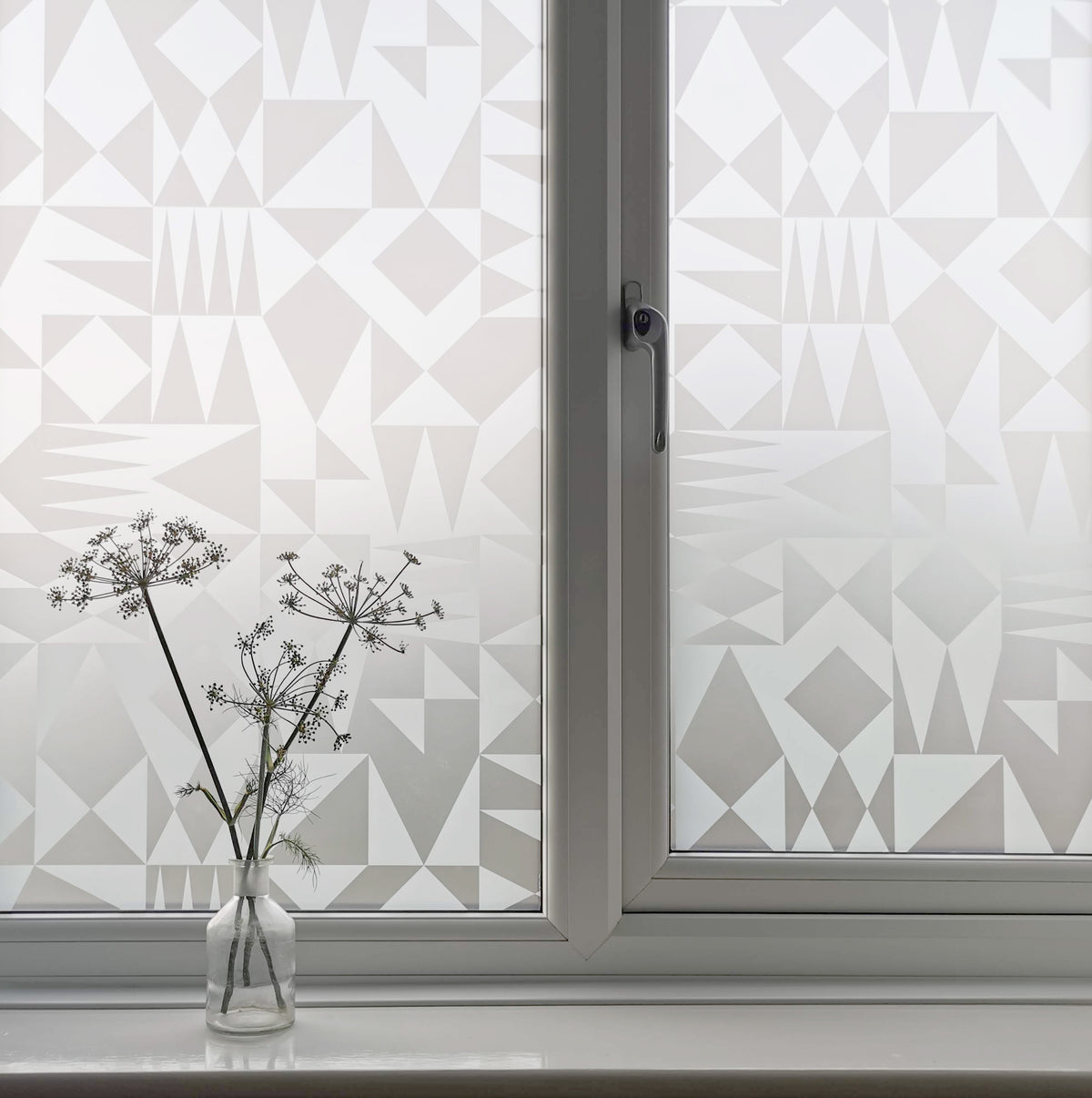 Window with geometric patterned film, vase with dried flowers on windowsill