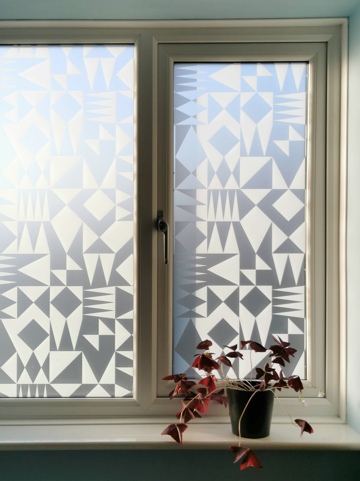 A window with a geometric pattern window film applied to the glass for privacy and decoration.