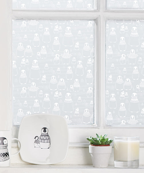Close up of a window with white frames and a repeated penguin design by helen Russell window film applied to the glass. 