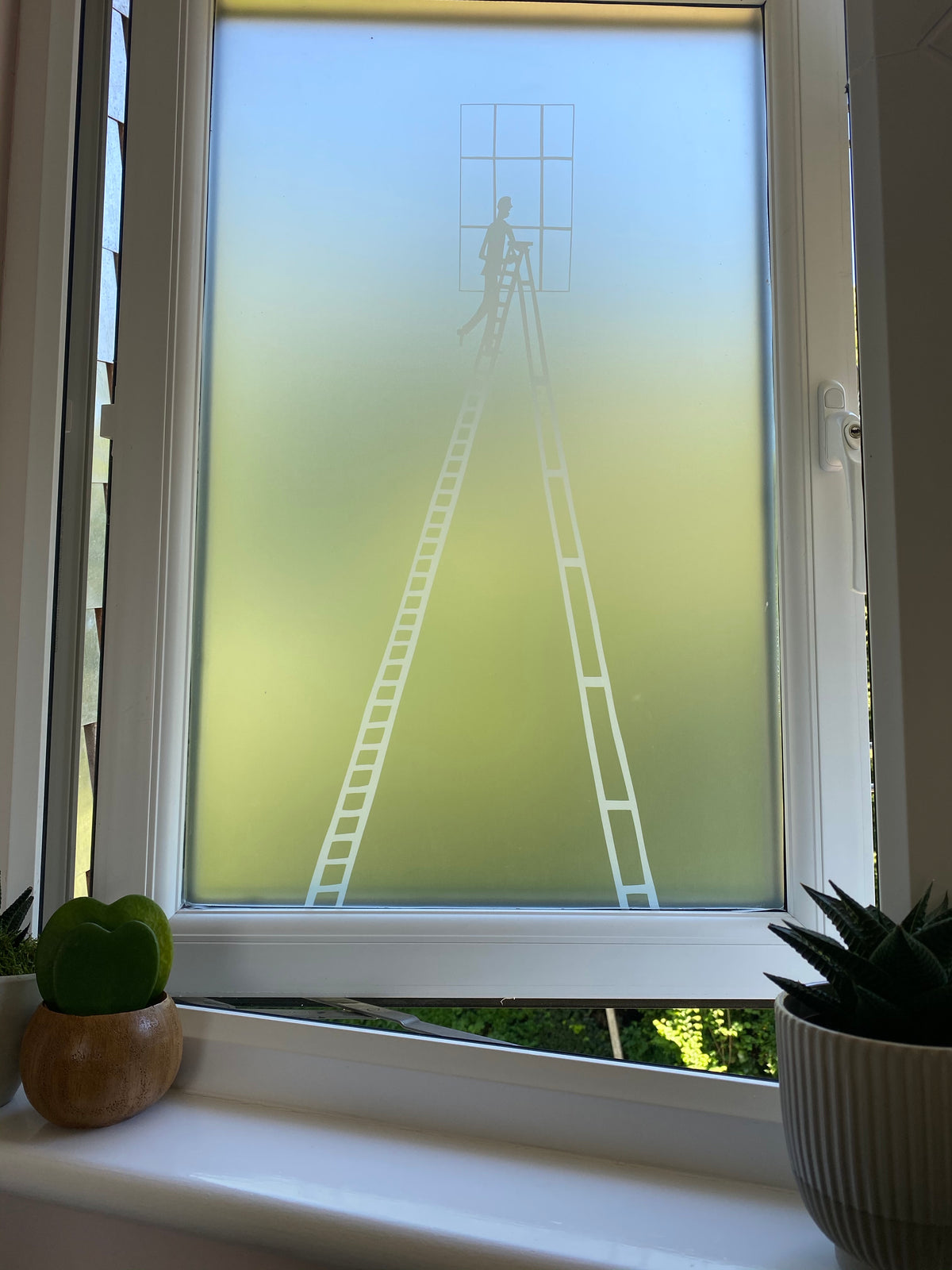 Open window with a white frame, with frosted window film featuring a white printed Rob Ryan design applied to it. 