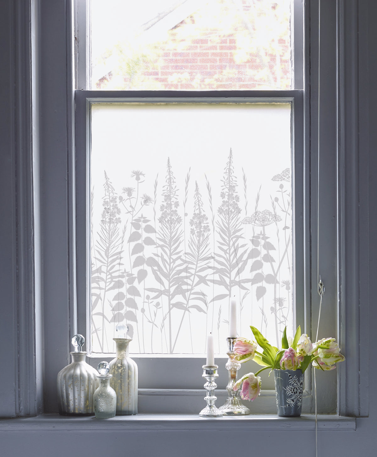 Decorative privacy window film with plant pattern on a blue window frame.