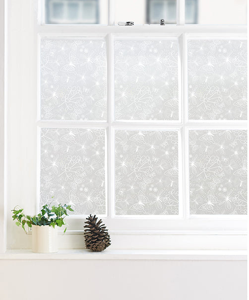 Decorative window film with repeated butterfly pattern on a window with white frames
