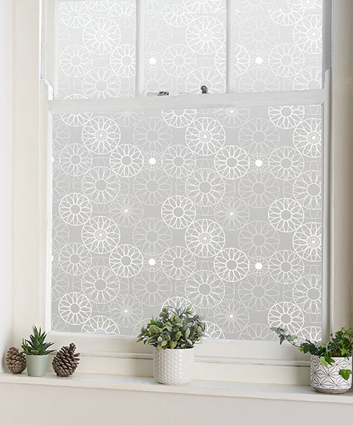 Decorative Helen Russell window film with geometric pattern printed onto frosted film on a window with plants on the window ledge.