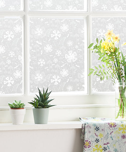 Decorative window film with floral pattern on a window with plants on the windowsill. 